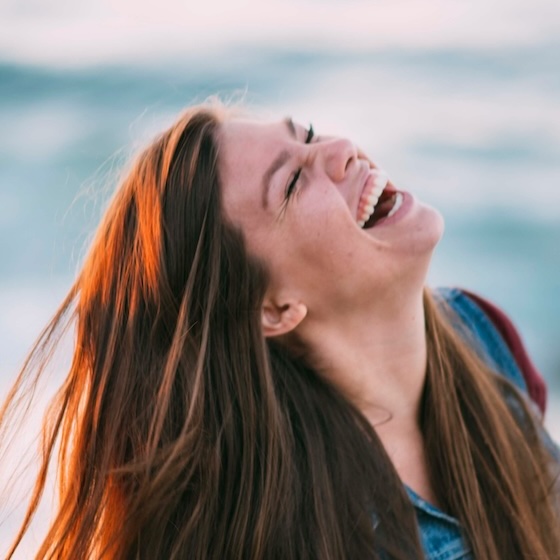 empowered and authentic woman laughing on the beach